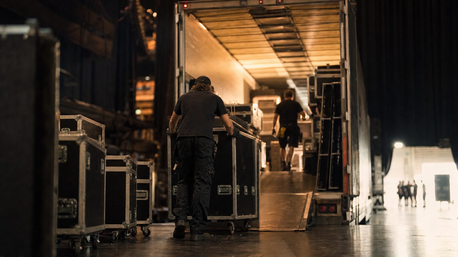 Production crew loading road cases into a truck at a venue