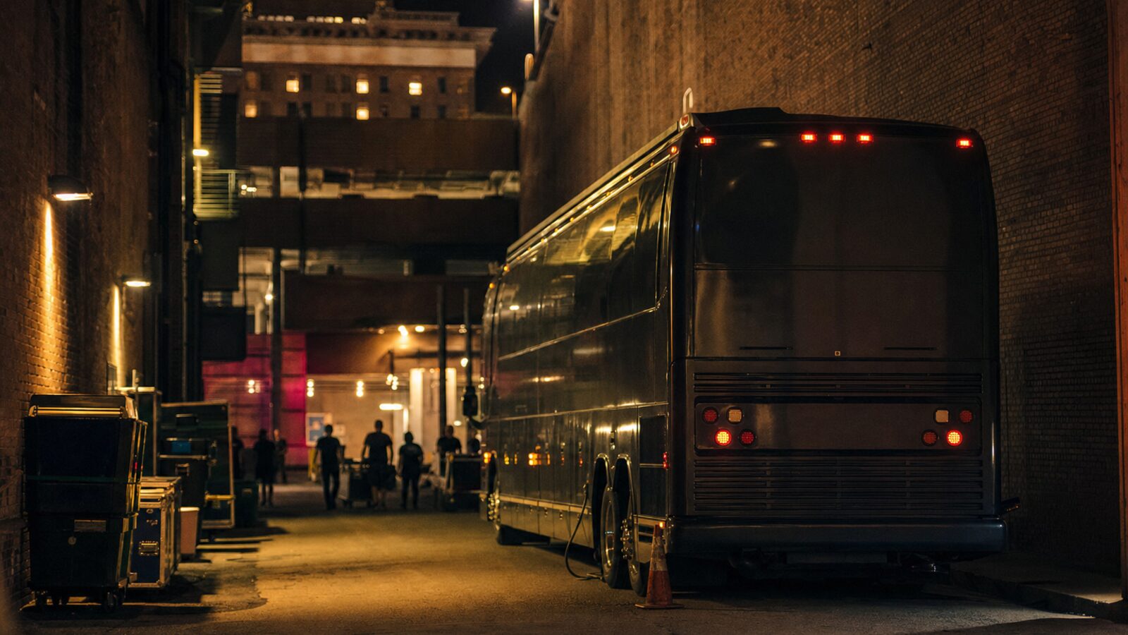 Touring sleeper bus parked behind a concert venue at night